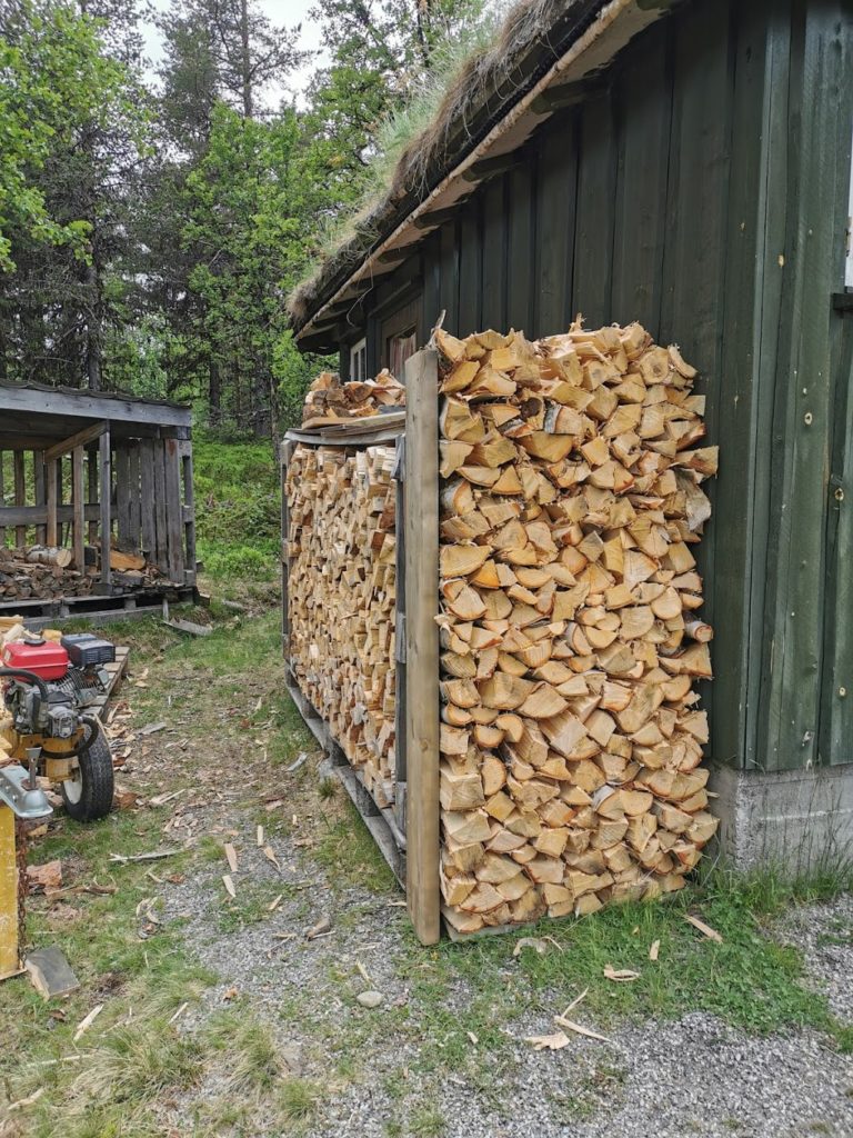 Ved som er kløyvd og stabla etter trefelling rundt hytta.